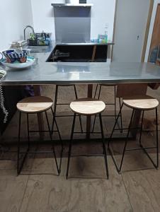 a kitchen counter with three stools under a table at Mountain Breeze Rarotonga in Arorangi +15 photos
