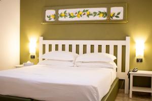 a bedroom with a white bed with two lights on it at San Domenico Residence by BADIA NUOVA in Trapani