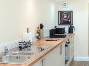 Rose Cottage, Kepwick Village with Hot Tub - Rural Location في Kepwick: كاونتر مطبخ مع حوض وصورة رجل