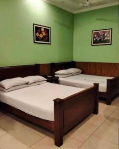 ラホールにあるHotel Indusの緑の壁の部屋にベッドが2つある