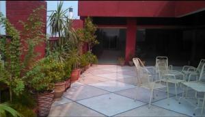 ラホールにあるHotel Indusの建物の前に植物が植えられたパティオ(椅子付)