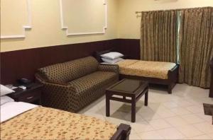 ラホールにあるHotel Indusのソファとベッドのあるホテルの部屋