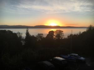 a sunset over a body of water with boats at A Baronial Hall apartment - great views of Loch Fyne  +2 photos