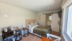 a bedroom with a bed and a table with a microwave at Camellia Cottage - Pool Room in Constantia