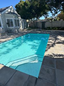 a swimming pool with blue water in a yard at Camellia Cottage - Pool Room in Meadowridge