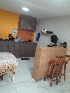 Eine Küche mit einem Tisch, zwei Stühlen und einer Theke in der Unterkunft Suíte Lemos Prêmio in Porto De Galinhas