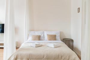 une chambre blanche avec un lit avec deux serviettes dessus dans l'établissement Trendy Apartments in Centrum, à Staré Mesto