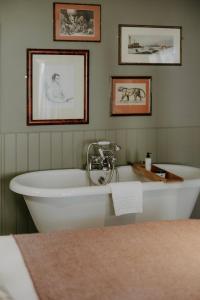 a bath tub in a room with pictures on the wall at The Bull And Swan in Stamford