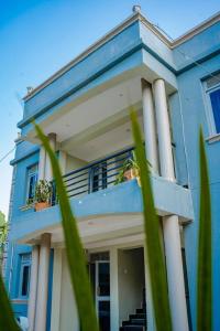 a blue house with a balcony with potted plants on it at BougainVille in Fort Portal