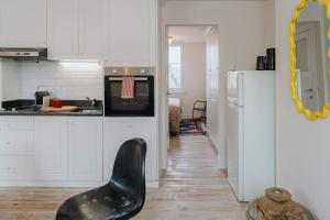 a kitchen with white cabinets and a black chair at Cozy Apartment in Central Antwerp in Antwerp