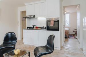 a kitchen with white cabinets and black chairs in a room at Cozy Apartment in Central Antwerp in Antwerp
