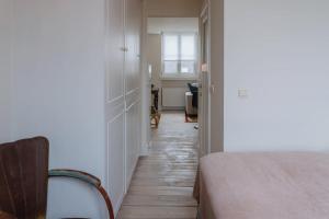 a hallway with a bed and a chair in a room at Cozy Apartment in Central Antwerp in Antwerp +13 photos