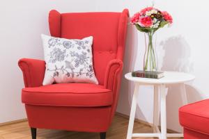 a red chair with a vase of flowers next to a table at Watzmann Panorama in Berchtesgaden