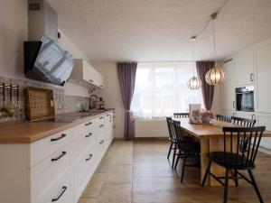 a kitchen with white cabinets and a wooden table at Ferienhäuschen Storchennest in Schönau am Königssee +14 photos