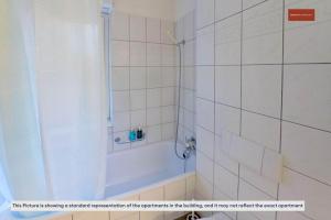 een wit betegelde badkamer met een douche en een bad bij Witikonstrasse 515 in Zürich