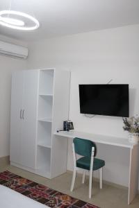 a white desk with a chair and a tv on a wall at Nestly Rooms in Sauk