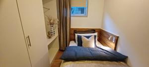 a small bedroom with a bed with blue and white pillows at Central apartment with 2 bedrooms in Tromsø