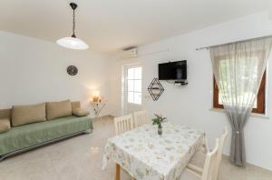sala de estar con mesa y sofá verde en Apartment San, en Povljana