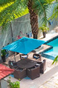 a table and chairs with a blue umbrella next to a swimming pool at House of Ivy in Trankill