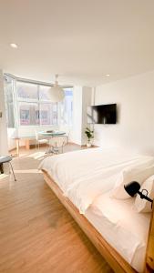 a white bedroom with a large bed and a table at The companions house in Sathani Bang Su
