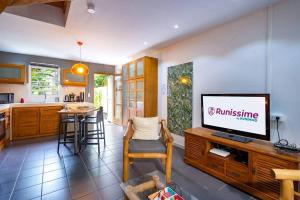 a living room with a tv and a kitchen at COTTAGE BAMBOU classé 3 étoiles - 4 à 6 personnes - 2 chambres - avec piscine privée et accès direct à la plage et à l'esplanade de Boucan Canot avec ses bars et restaurants in Saint-Gilles les Bains