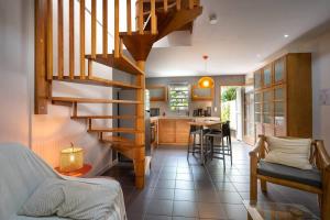 a living room and kitchen with a spiral staircase at COTTAGE BAMBOU classé 3 étoiles - 4 à 6 personnes - 2 chambres - avec piscine privée et accès direct à la plage et à l'esplanade de Boucan Canot avec ses bars et restaurants in Saint-Gilles les Bains