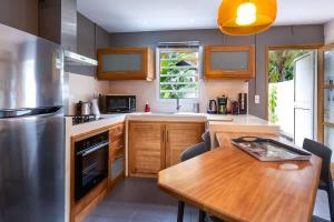 a kitchen with a wooden table and a stainless steel refrigerator at COTTAGE BAMBOU classé 3 étoiles - 4 à 6 personnes - 2 chambres - avec piscine privée et accès direct à la plage et à l'esplanade de Boucan Canot avec ses bars et restaurants in Saint-Gilles les Bains