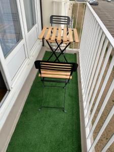 eine Bank und zwei Stühle auf einer Veranda mit grünem Gras in der Unterkunft Appartement agréable Orleans centre-ville in Orléans