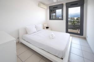 a white bedroom with a white bed and a window at ROYCE classé 3 étoiles - Appartement 4 personnes - Vue mer - idéalement situé sur le front de mer et à 200 m du lagon de ST-PIERRE in Saint-Pierre
