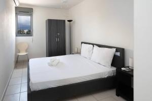 a bedroom with a white bed with a black headboard at ROYCE classé 3 étoiles - Appartement 4 personnes - Vue mer - idéalement situé sur le front de mer et à 200 m du lagon de ST-PIERRE in Saint-Pierre