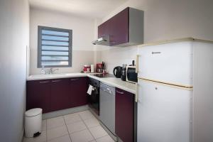 a small kitchen with a white refrigerator and a window at ROYCE classé 3 étoiles - Appartement 4 personnes - Vue mer - idéalement situé sur le front de mer et à 200 m du lagon de ST-PIERRE in Saint-Pierre