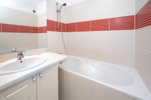 a bathroom with a tub and a sink and a bath tubermottermott at ROYCE classé 3 étoiles - Appartement 4 personnes - Vue mer - idéalement situé sur le front de mer et à 200 m du lagon de ST-PIERRE in Saint-Pierre