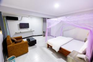 a bedroom with a bed and a chair and a tv at Jade Inn in Arusha