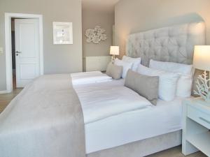 a large white bed with white sheets and pillows at Techts Strandhaus in Timmendorfer Strand
