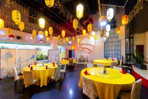 a restaurant with yellow tables and chairs and lights at Jade Inn in Arusha