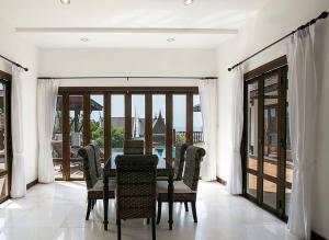 Un comedor con mesa y sillas y puertas de cristal. en Villa i Mae Phim med privat pool och havsutsikt, en Mae Pim