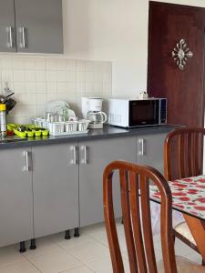 y cocina con encimera, microondas y mesa. en Haut de villa Espérenza, en Les Abymes