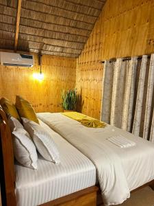 a bedroom with a bed with white sheets and pillows at THE WOODEN HOUSE in Msaranga