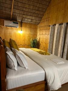 a bedroom with a bed with white sheets and pillows at THE WOODEN HOUSE in Msaranga