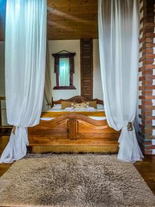 a bedroom with a wooden bed with white curtains at Villa Vejini cabin in Mamkoda