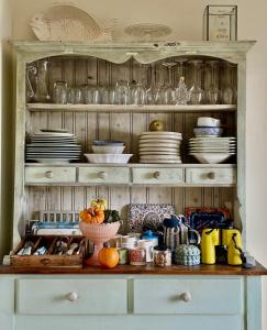 une armoire remplie de plats et d'assiettes sur une étagère dans l'établissement Seaside Cottage Kinsale, à Feevaghmore