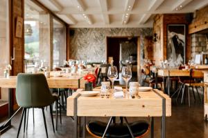 a restaurant with wooden tables and wine glasses at Hôtel Les Roches Fleuries in Cordon
