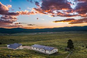 una casa en medio de un campo con una puesta de sol en Angel Fire Home Sangre de Cristo Mountains View!, en Angel Fire