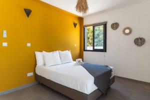 a bedroom with a large bed with a yellow wall at VILLA Ô 3 CAP - Magnifique Villa - classée 4 étoiles - Piscine CHAUFFEE - 4 ch - 8 personnes - accès direct à la plage et à l'esplanade de BOUCAN CANOT in Saint-Gilles les Bains