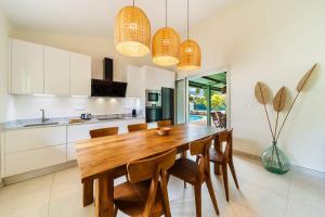 VILLA EMERAUDE - A 200m du magnifique lagon de l'Hermitage à ST GILLES LES BAINS - Villa 3 chambres avec piscine في Saint-Paul: مطبخ وغرفة طعام مع طاولة وكراسي خشبية +7 صور