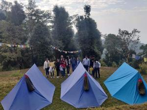 a group of people standing in a field with tents at Himachal Adventure in Dharamshala