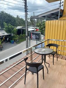 a table and two chairs on a balcony with a table and a table and chairs at PROpaganda Guest House in Thongsala