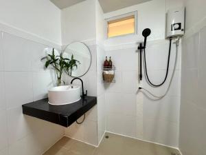 a white bathroom with a sink and a mirror at PROpaganda Guest House in Thongsala