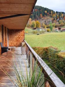 un porche de madera con una valla y un campo en ALMMONTE LIGNUM Lodge, en Wagrain