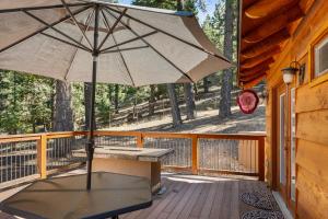 eine Terrasse mit einem Tisch und einem Sonnenschirm auf einem Deck in der Unterkunft All in Cabin in Big Bear Lake